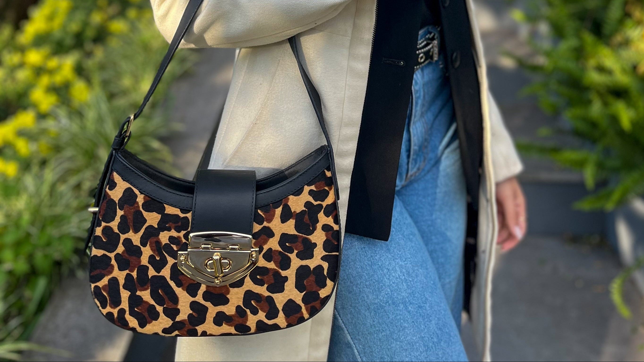 Woman holding a leopard print handbag outdoors on a sunny day