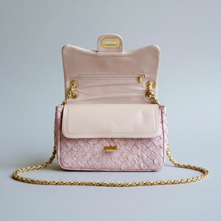Pink quilted handbag with gold chain on a light gray background