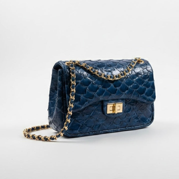 Blue pirarucu textured handbag with a chain strap on a light gray background