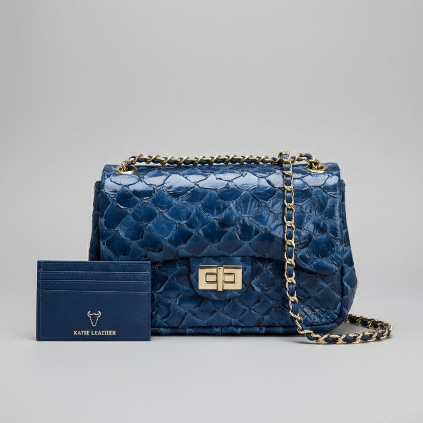 Blue textured handbag with gold chain and matching cardholder on a gray background