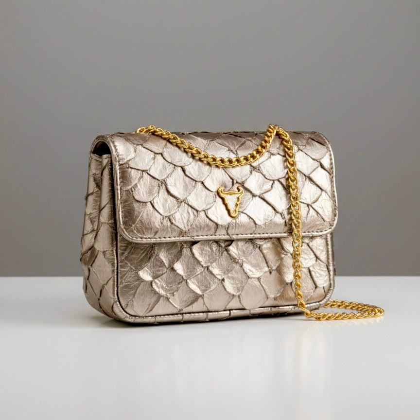 Gold quilted handbag with chain strap on a gray background