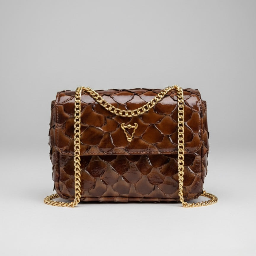 Brown quilted handbag with gold chain on a gray background