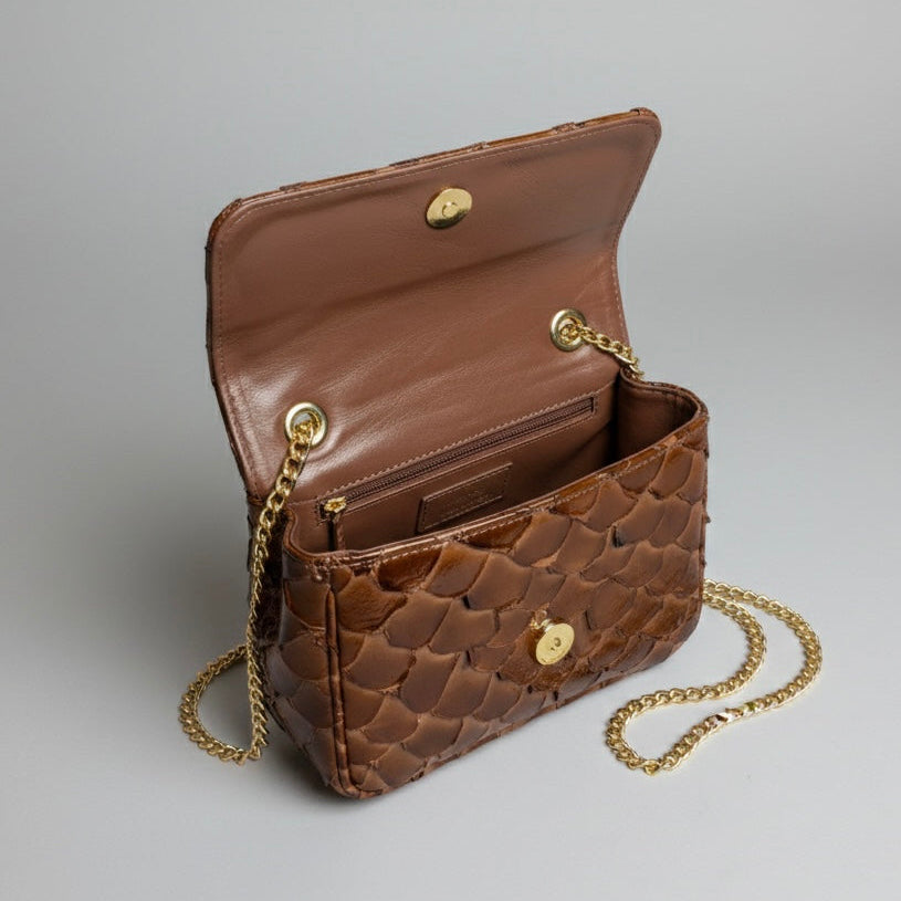 Brown quilted handbag with gold chain on a gray background