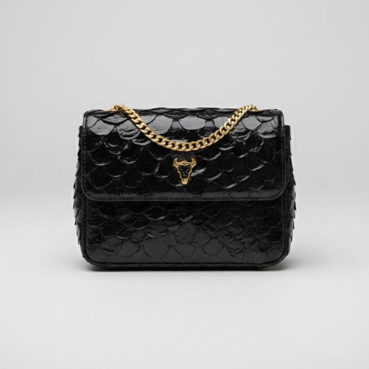 Black quilted handbag with gold chain on a light gray background. pirarucu bags