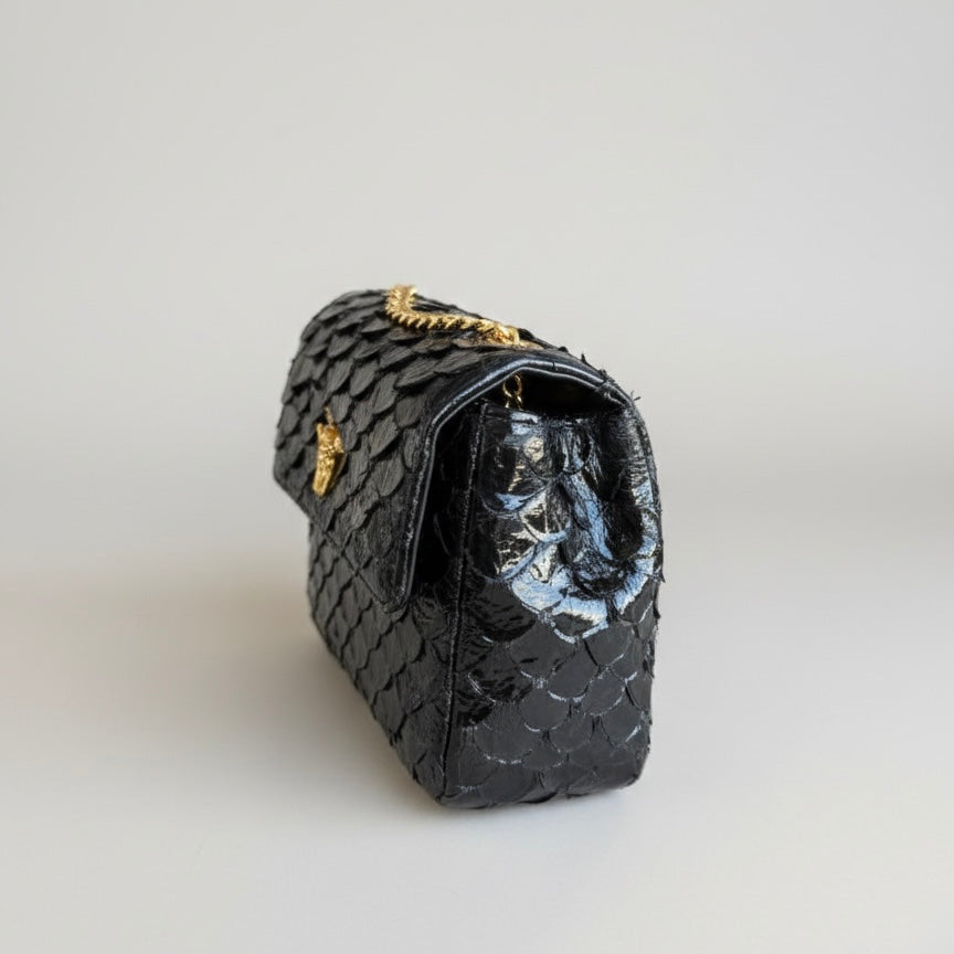 Black quilted handbag with gold accents on a light gray background, pirarucu bags