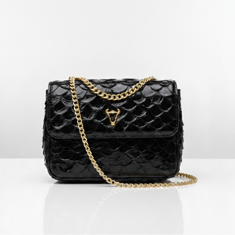 Black quilted handbag with gold chain strap on a white background. pirarucu bags